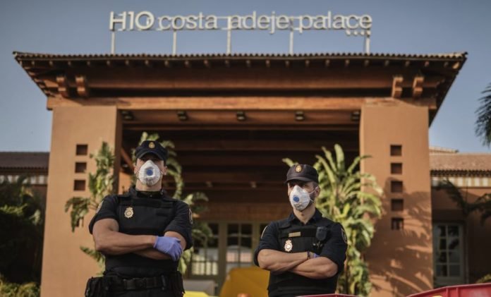Policías con máscaras protectoras montan guardia frente al hotel H10 Costa Adeje Palace, en la isla canaria de Tenerife, España, que está en cuarentena por coronavirus. (Foto AP).
