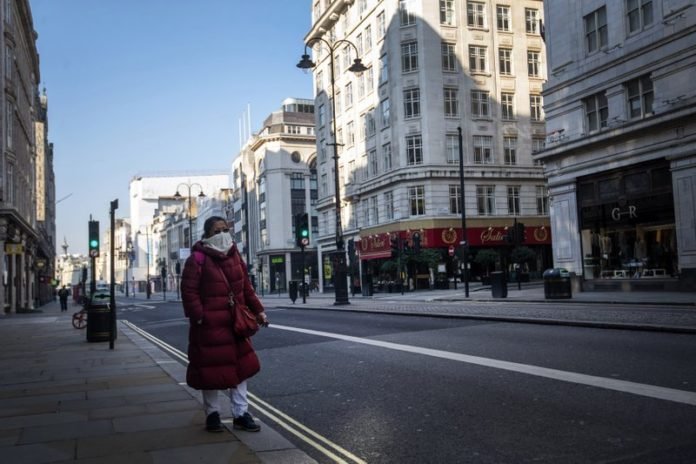 Una mujer camina por la calle Strand en lo que suele ser la hora pico en Westminster, Londres, el martes 26 de marzo de 2020. (Victoria Jones/PA via AP)